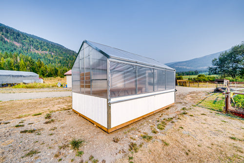 Harvest greenhouse with polycarbonate roof and white skirt, Okanagan mountains behind