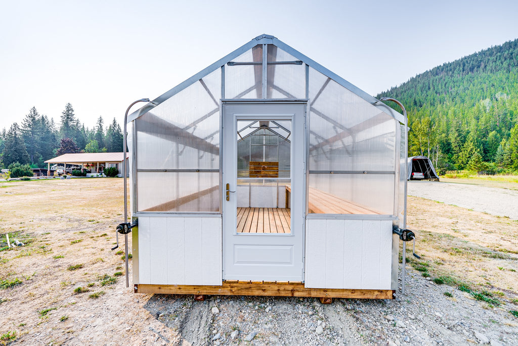 Front view of the Harvest greenhouse with storm door open onto the plank deck