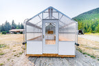 Front view of the Harvest greenhouse with storm door open onto the plank deck