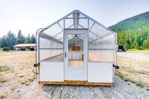 Front view of the Harvest greenhouse with storm door open onto the plank deck