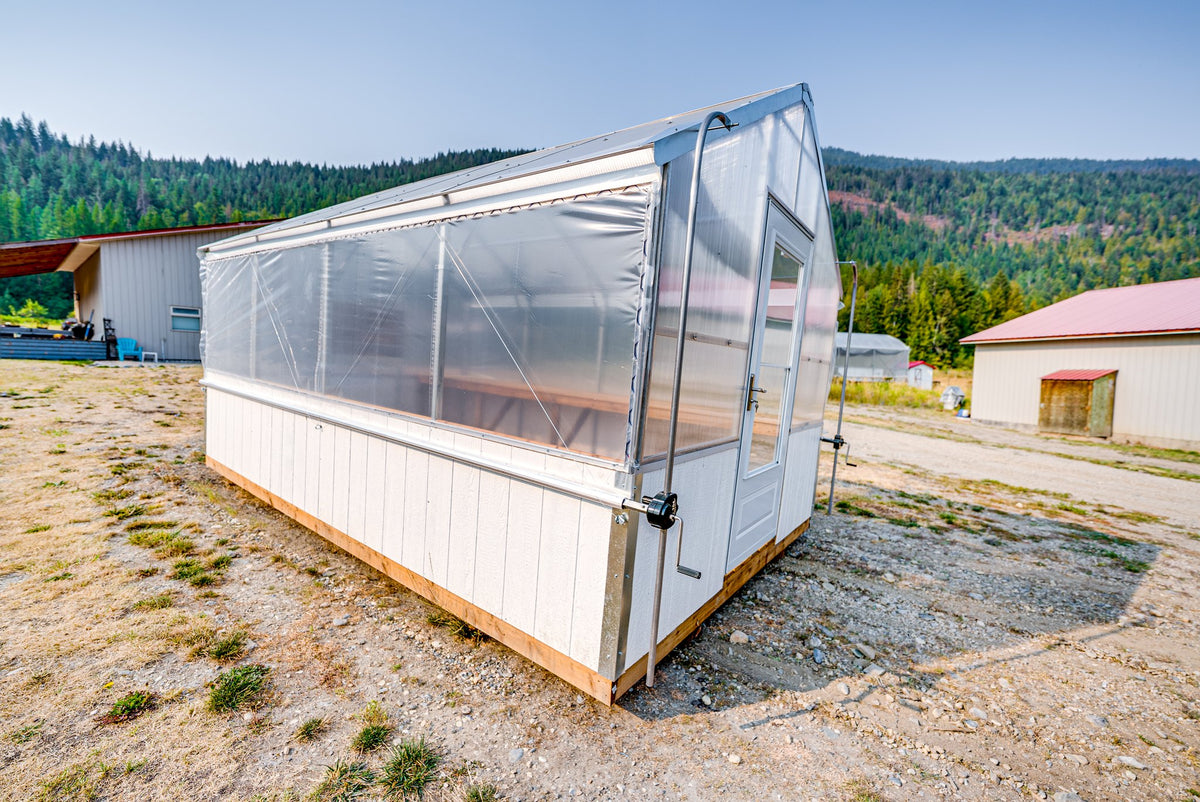 Harvest greenhouse in afternoon sun, Shuswap hillside behind